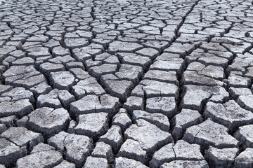 Beautiful deep cracks in the ground, gray background texture. Selective focus at wide cracks in dry soil. Effects of heat and drought.Concept of global warming, greenhouse effect. Earth climate change