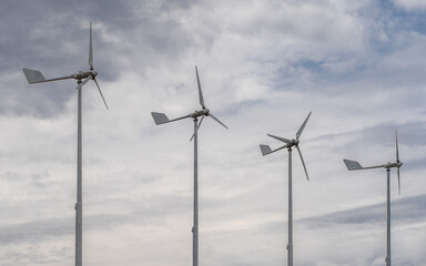 Four small wind turbines in the background of clouds. Environmentally friendly source of energy....