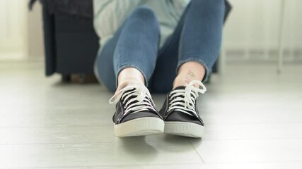 Close-up of a woman's legs in sneakers, a woman sits on the floor and moves her legs Slow motion HD