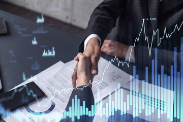A handshake symbolize a capital market transaction to proceed profit in stock trading. Financial hologram chart over the table with the document. Women in business concept.