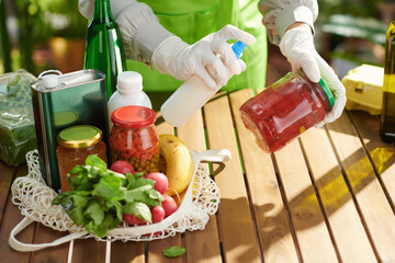Housewife in kitchen disinfecting groceries after supermarket