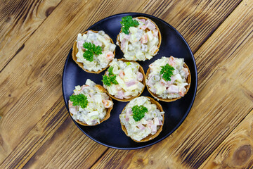 Traditional Russian festive salad Olivier in tartlets on wooden table