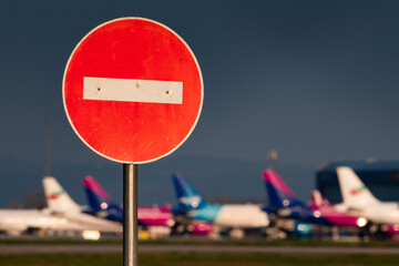 A no entry road sign before a bunch of grounded airplanes representing the crisis in aviation caused by the Covid-19 pandemics