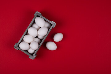 Eggs in a wooden box on a red background. Copy space.