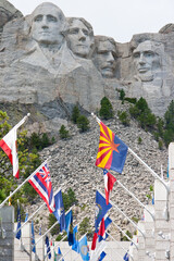 Vertical shot of Mount Rushmore with the sculpted heads of US Presidents seen through flags