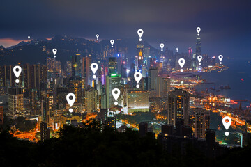 Map pin icons on Hong Kong's cityscape at night. Lit skyscrapers on Hong Kong Island in Hong Kong, China, viewed from above at dusk.