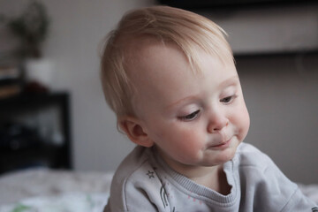 Close-up. A little girl aged one or two years old with a focused business face. Funny children facial expressions. The fair-haired baby is fascinated by something