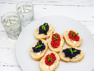 sandwiches with fish roes on a plate and vodka aside