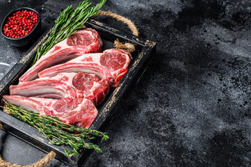 Raw lamb meat chops steaks in a wooden tray. Black background. Top view. Copy space