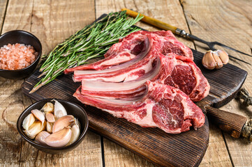Lamb raw cutlets chops  with salt, pepper and garlic. wooden background. Top view