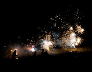 Fireworks Explode All Over Beach with People in Silhouette - 429099858
