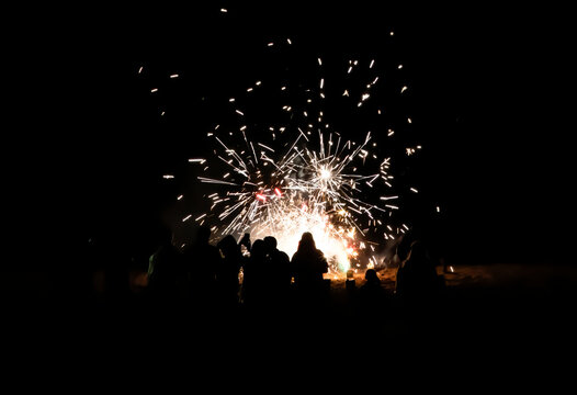 People Watch Fireworks on Beach at Night and Take Selfies