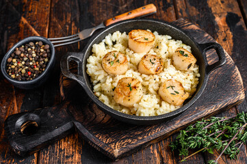 Seafood Risotto with Scallops in a pan. Dark wooden background. Top view