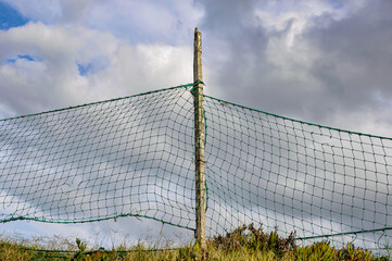 A net fence on the grass with the sky behind