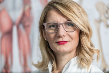 Blonde female physician doctor standing in Her office. Portrait of friendly smiling woman-physician. Medicine concept