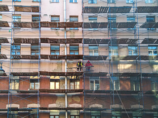 Construction workers on the scaffold around old renovating building