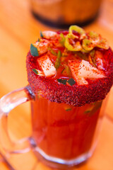 Michelada beer with tomato juice. Clamato with beer on wooden table. Mexican drink. Michelada beer with tomato juice, shrimps, clam and lemon, mexican drink cocktail in mexico. Concept of mexican beer