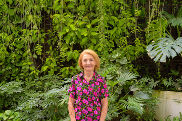 Portrait of a senior woman smiling outdoors at garden during summer