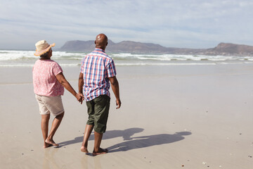 Senior african american couple holding hands walking on the beach
