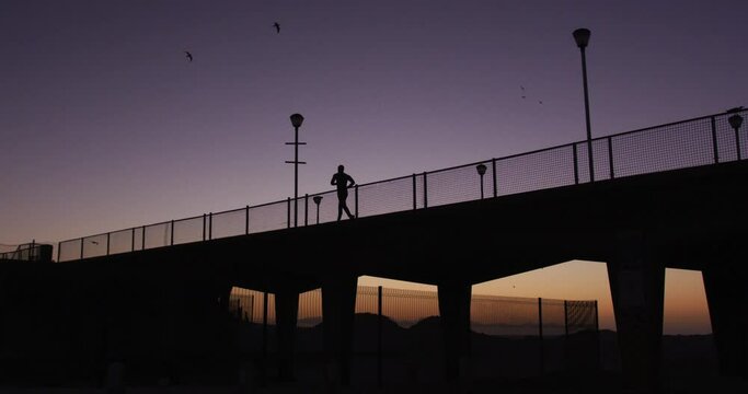 Silhouette of man running on bridge in the evening