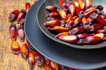 Pine cone and pine nuts (typical araucaria seed used as a condiment in Brazilian cuisine). Pine nuts, typical winter food on wooden background.