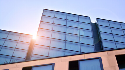 Blue sky reflection in glass facade of building. View of office building windows close up with sunrise, reflection and perspective.. Glass facade on a bright sunny day with sunbeams on the blue sky. 