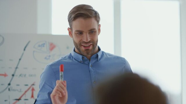 Confident man presenting startup office. Male speaker consulting team