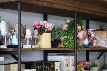 Collection of goods on display in boutique fashion store featuring wooden carved whale statues and fake flowers