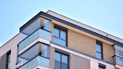 A fragment of modern architecture, walls and glass. Windows and balconies of a residential building against a blue sky. Detail of New luxury house and home complex. Part of city real estate property a