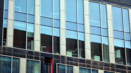 The glazed facade of an office building with reflected sky. Modern architecture buildings exterior background. Clouds sky reflection.