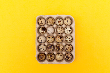 Obraz na płótnie Canvas Quail eggs in package on yellow background. Top view, copy space