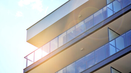 Detail of new luxury house and home complex. Glass surface with sunlight. Rising sun on the horizon. Part of modern residential apartment with flat building exterior. 