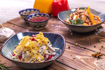 A set of dishes with salads on a wooden table decorated with spices, garlic, rosemary.
