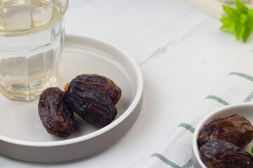 Kurma dan Air Putih, Medjool Dates and water on marble white background. Breakfasting concept in Ramadan month. Islamic template for text background. 