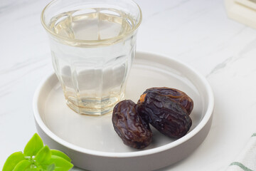Kurma dan Air Putih, Medjool Dates and water on marble white background. Breakfasting concept in Ramadan month. Islamic template for text background. 