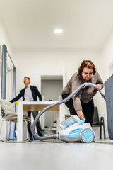 Front view full length portrait of senior caucasian woman adjusting turning on or off vacuum cleaner while cleaning at home in room real people housework concept