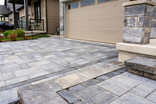 Luxury hardscape driveway shows pavers with pattern and  and matching landing and step.