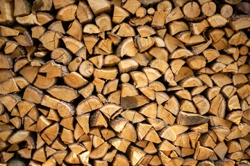 Tuinposter muur brandhout, achtergrond van droog gehakte brandhout logs in een stapel. © InfiniteStudio