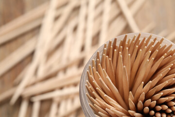 Wooden toothpicks in holder, closeup. Space for text