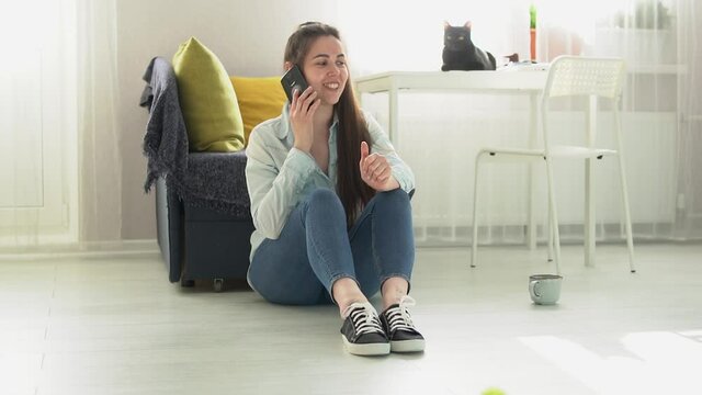 young woman sits on the floor at home and talking on the phone Slow motion HD