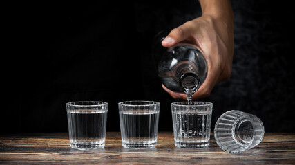 Barman pouring tequila into four shots