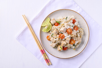 Fried rice with tofu, mung bean sprouts and tomato on dish with chopsticks on white background, Asian healthy vegan food