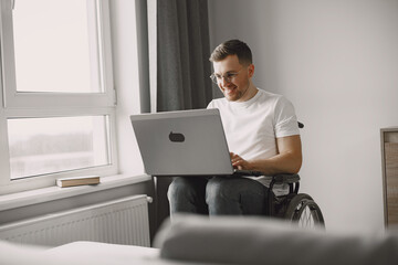 Young man in wheelchair using laptop working at home