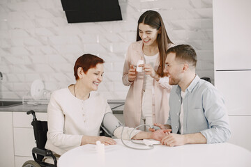 Couple helping disabled mother measure blood pressure