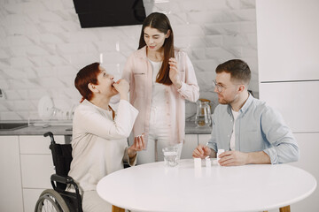 Couple helping disabled mother take in medicines