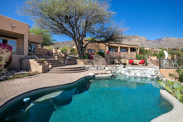 Swimming pool with hot tub and terraced patio at a luxury home in a desert environment.