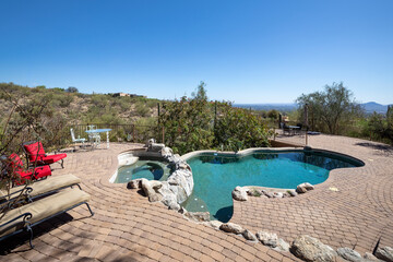 Swimming pool with hot tub and terraced patio at a luxury home in a desert environment.