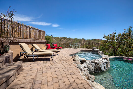 Swimming pool with hot tub and terraced patio at a luxury home in a desert environment.