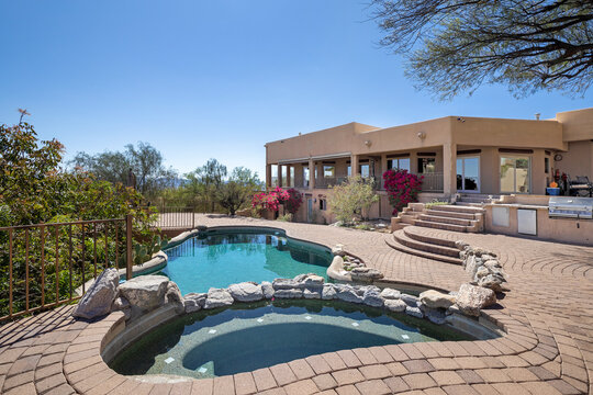 Swimming pool with hot tub and terraced patio at a luxury home in a desert environment.