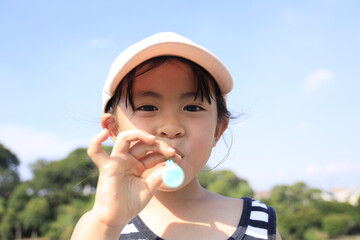 シャボン玉で遊ぶ幼児(5歳児)と青空